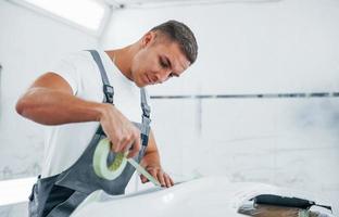 Detailed work. Caucasian automobile repairman in uniform have job in garage photo
