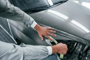 Detailed work. Caucasian automobile repairman in uniform have job in garage photo