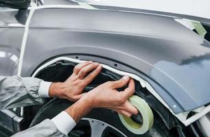 Detailed work. Caucasian automobile repairman in uniform have job in garage photo