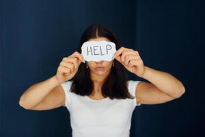 Young scared woman holds sign and ask for help. Conception of domestic violence photo