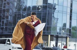 Running, late for the work. Young man in pajama is outdoors on the street. Feels sleepy photo