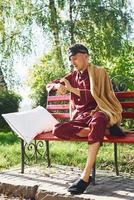 Lying down on bench in park. Young man in pajama is outdoors on the street. Feels sleepy photo