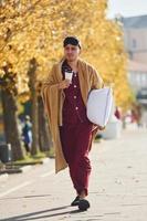 Morning coffee cup. Young man in pajama is outdoors on the street. Feels sleepy photo