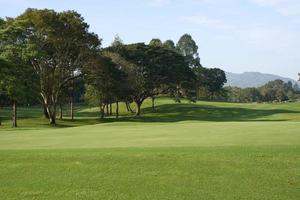 la belleza del campo de golf tiene montañas detrás. foto