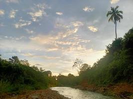 hermoso paisaje natural en el cielo azul, nubes blancas y muchos árboles verdes a su alrededor foto