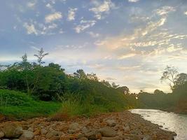 beautiful natural scenery in the blue sky, white clouds and many green trees around it photo