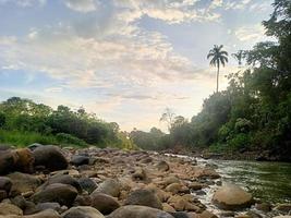 beautiful natural scenery in the blue sky, white clouds and many green trees around it photo