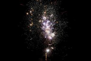Bright and colorful firework sparks and explosions at a dark black night sky photo