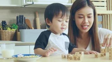 Asian mother and son play wooden jigsaw puzzle together happily. Love and relationship between mother and child video