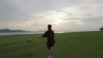 vrouw rennen in weide Bij zonsondergang terwijl op reis naar platteland