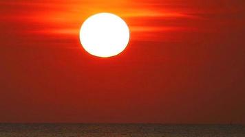 zoom coucher de soleil sur la mer et nuage rouge foncé sur le ciel en été, voir le soleil oméga sur la mer video