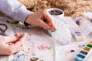 Children's hands take a bead and boxes with beads for weaving a bracelet photo