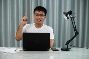 You got me. Happy charming male entrepreneur in formal blue shirt raising index finger and shaking forefinger at camera joyfully laughing and smiling at camera being pleased with good joke photo