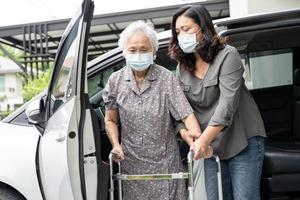 Caregiver help and support asian senior or elderly old lady woman patient walk with walker prepare get to her car, healthy strong medical concept. photo