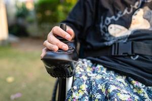 mujer asiática paciente en silla de ruedas eléctrica con joystick y control remoto en la sala del hospital de enfermería, concepto médico fuerte y saludable foto