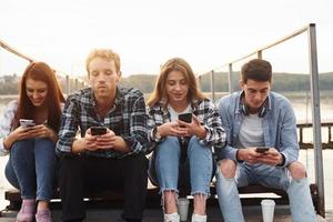 Near the lake. Group of young cheerful friends that is outdoors having fun together photo