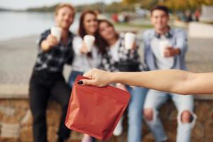 Red package of coffee. Group of young cheerful friends that is outdoors having fun together photo