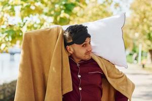 Young man in pajama is outdoors on the street. Feels sleepy photo