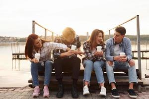 cerca del lago. grupo de jóvenes amigos alegres que están al aire libre divirtiéndose juntos foto