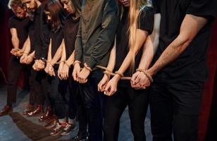con cuerda en las manos. grupo de actores con ropa de color oscuro ensayando en el teatro foto