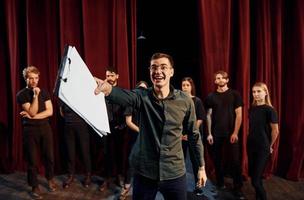Man is practicing his role. Group of actors in dark colored clothes on rehearsal in the theater photo