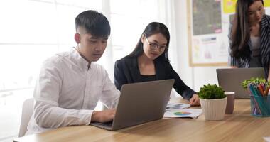 mentore allenatore porzione asiatico femmina bicchieri dipendente con aziendale Software. tailandese colleghi Lavorando su progetto insieme a gruppo incontro. discutere statistiche, utilizzando computer portatile, manager consulenza cliente video