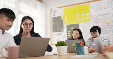 Asian business team meeting in meeting room. Employee working on laptop in office. Confident young female glasses mentor corporate leader manager counselor communicate. video