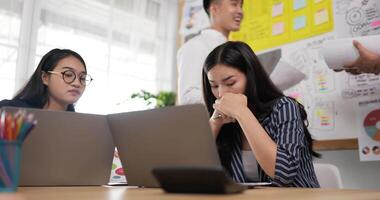 tenue à la main d'une femme d'affaires asiatique heureuse qui consulte une collègue à lunettes dans la salle de réunion. entraîneur de mentor féminin joyeux à la négociation. formation de collègues d'entreprise à la salle de conférence. video