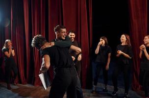 escena de lucha. grupo de actores con ropa de color oscuro ensayando en el teatro foto