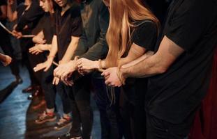 con cuerda en las manos. grupo de actores con ropa de color oscuro ensayando en el teatro foto