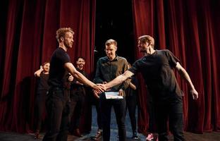 Working together. Group of actors in dark colored clothes on rehearsal in the theater photo