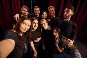 Making selfie. Group of actors in dark colored clothes on rehearsal in the theater photo