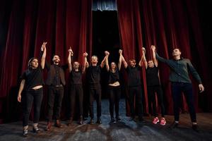 gente inclinándose ante la audiencia. grupo de actores con ropa de color oscuro ensayando en el teatro foto