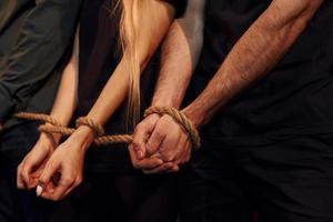 Knot in the hands. Group of actors in dark colored clothes on rehearsal in the theater photo