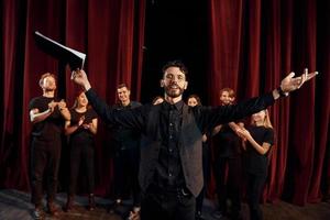 Man is practicing his role. Group of actors in dark colored clothes on rehearsal in the theater photo