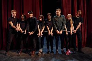 With rope in hands. Group of actors in dark colored clothes on rehearsal in the theater photo