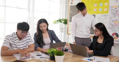 Asian man team leader coach mentor talk to diverse employee in office explain strategy at corporate group meeting. Asian workers discussing together in conference room during meeting at office. video