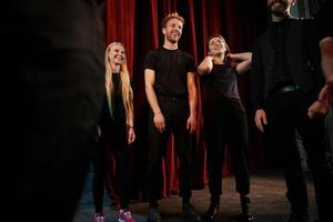 Practice in progress. Group of actors in dark colored clothes on rehearsal in the theater photo