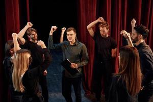 práctica en curso. grupo de actores con ropa de color oscuro ensayando en el teatro foto