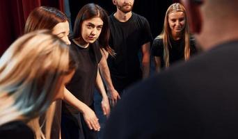 grupo de actores con ropa de color oscuro ensayando en el teatro foto