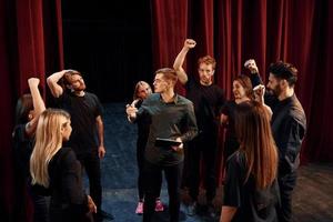 práctica en curso. grupo de actores con ropa de color oscuro ensayando en el teatro foto