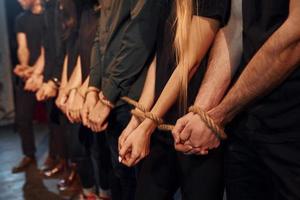 Knot in the hands. Group of actors in dark colored clothes on rehearsal in the theater photo