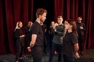 Eye contact practice. Group of actors in dark colored clothes on rehearsal in the theater photo