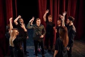 práctica en curso. grupo de actores con ropa de color oscuro ensayando en el teatro foto