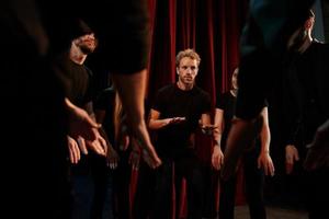 Practice in progress. Group of actors in dark colored clothes on rehearsal in the theater photo