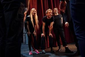 práctica en curso. grupo de actores con ropa de color oscuro ensayando en el teatro foto