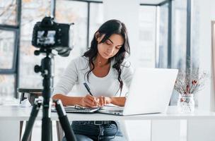 Camera recording girl. Young female freelancer working indoors in the office at daytime photo