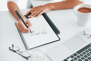 Close up view of young female freelancer that working indoors in the office at daytime photo