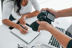 fotógrafo en el trabajo. dos jóvenes mujeres independientes en el interior de la oficina durante el día foto