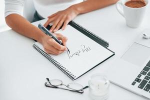 Close up view of young female freelancer that working indoors in the office at daytime photo